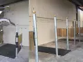 Aménagement d'une **dimension aire de pansage chevaux** avec tapis antidérapants et poteaux de contention. Un système de levage est visible.