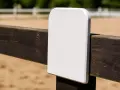 Un panneau blanc vierge sur une clôture en bois dans une carrière de dressage.