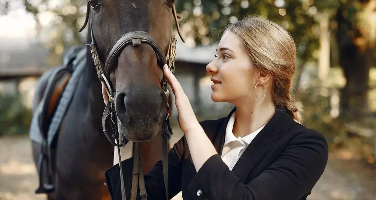 Une jeune femme caresse la tête d'un cheval noir, prête pour une séance de dressage équestre.